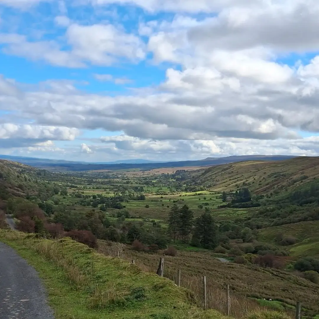 The view down a green glen in North Leitrim, hills on either side under a bright sky